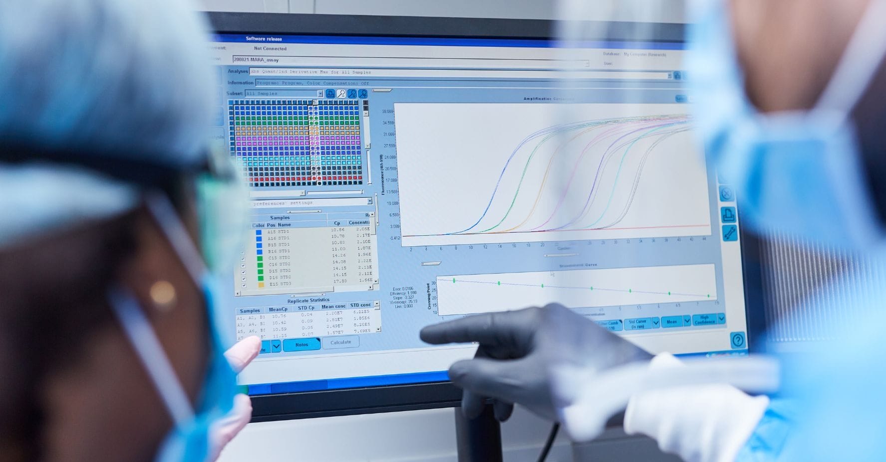 up to data Multi-Run Assay Control Solutions | Laboratory scientist analyzing data on computer screen with colorful charts and graphs while wearing protective gloves